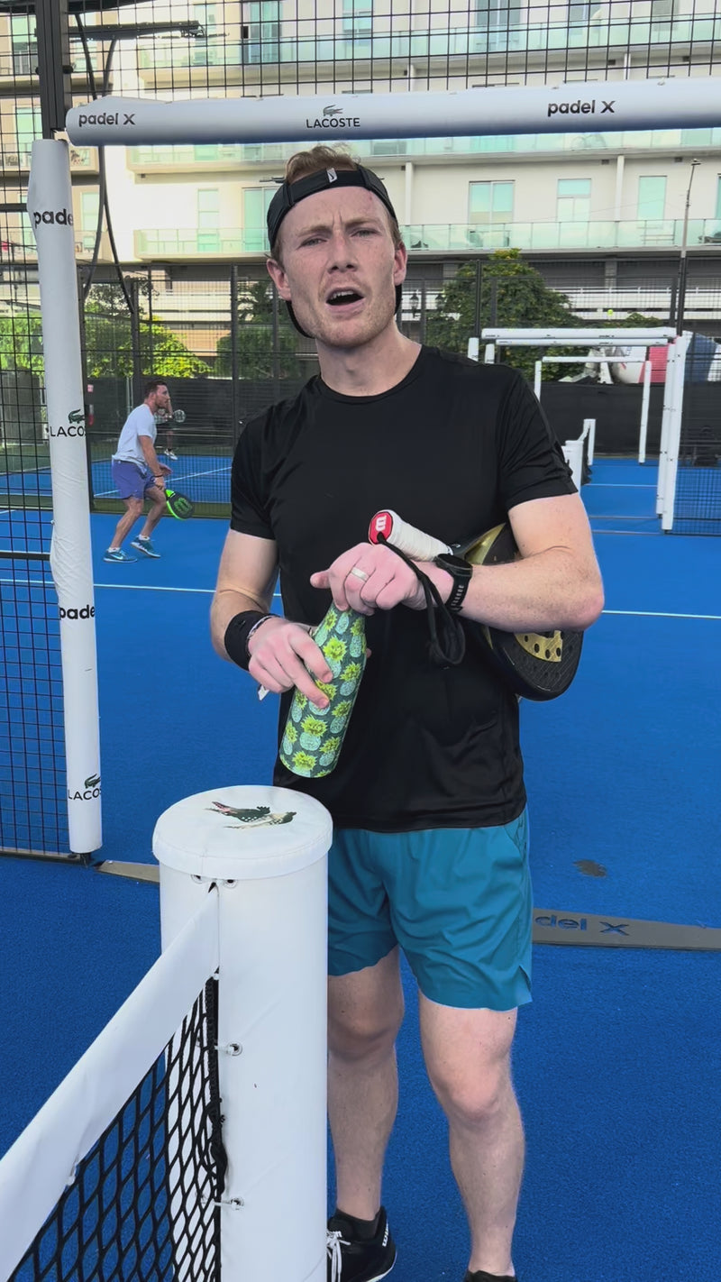A man with a sports racket and water bottle in hand tries Vibras before a padel match