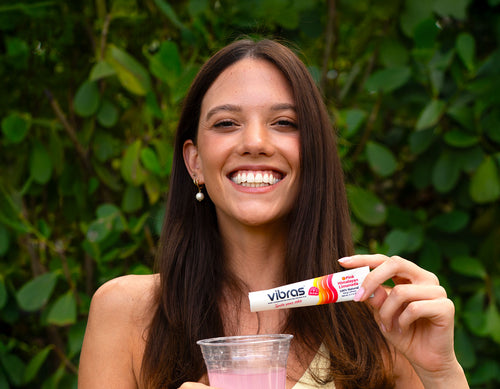 Woman holding a Vibras product in front of a green leafy background
