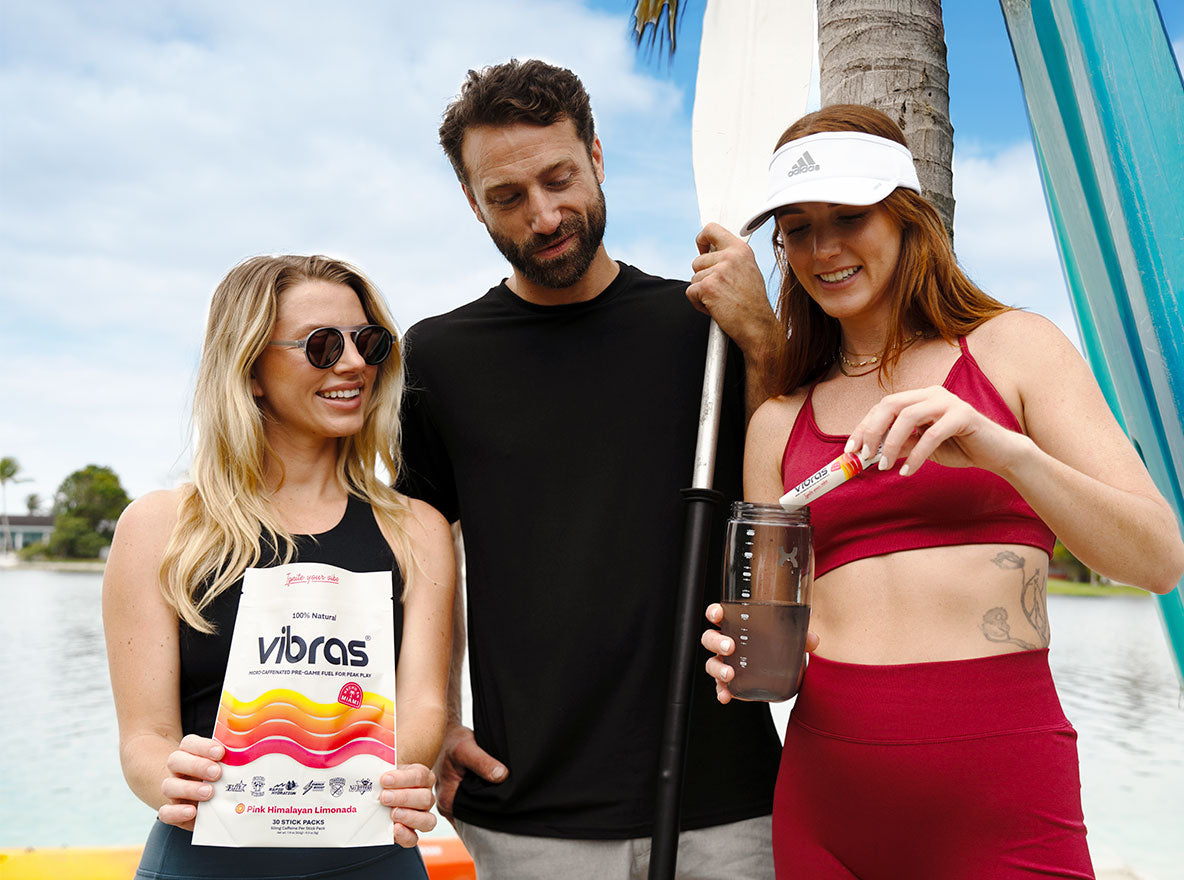 Two girls and a guy watch as the girl pours Vibras into a sports bottle